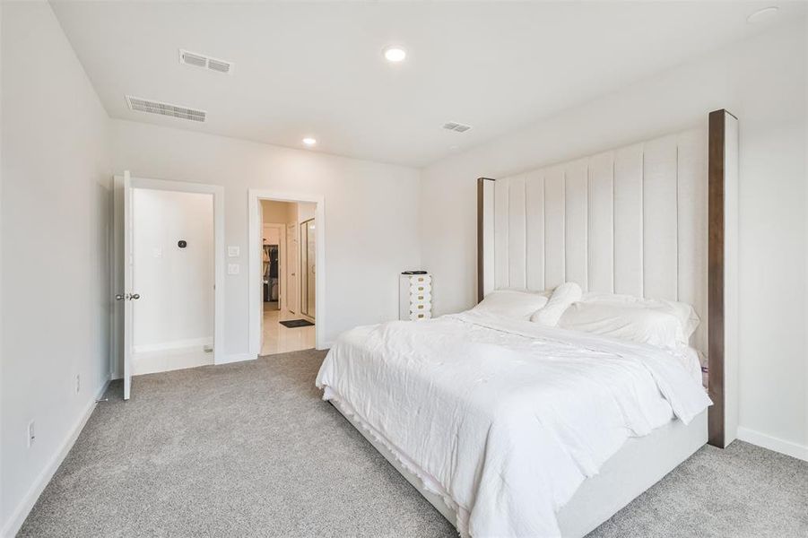 This is a bright and cozy bedroom featuring plush carpeting, and an en suite bathroom. There is also a spacious walk-in closet, providing ample storage space.
