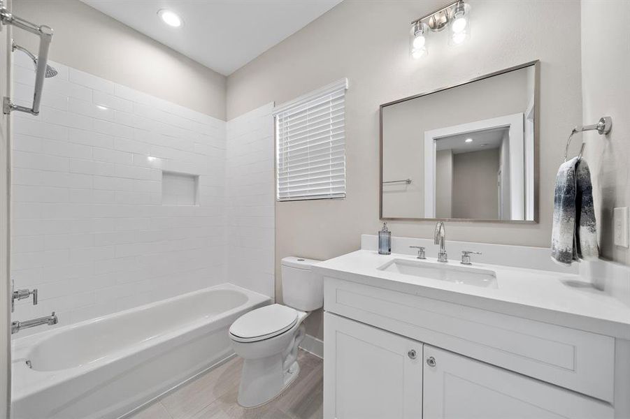 Full Bathroom with white cabinetry, Quartz counter tops, tub/shower with tile surround and an extended mirror.