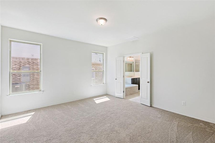 Unfurnished bedroom featuring light carpet and ensuite bathroom