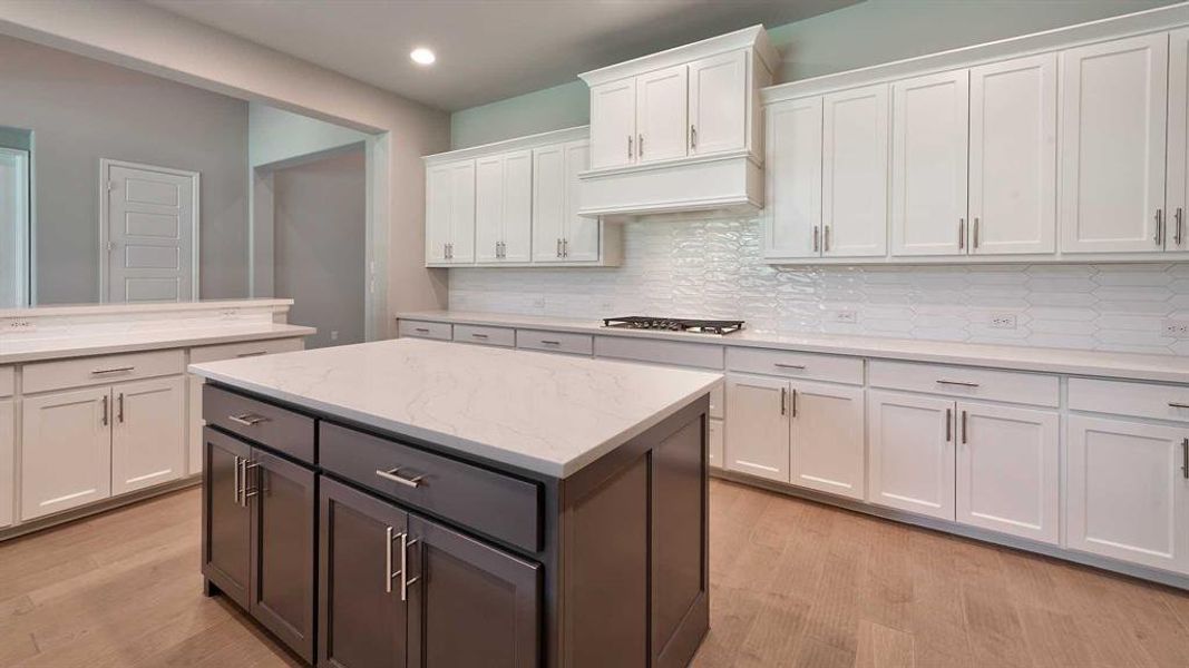 Kitchen with light hardwood / wood-style floors, white cabinetry, a center island, and decorative backsplash