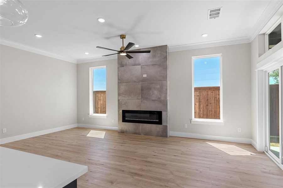 Unfurnished living room with ornamental molding, light hardwood / wood-style floors, ceiling fan, and a fireplace