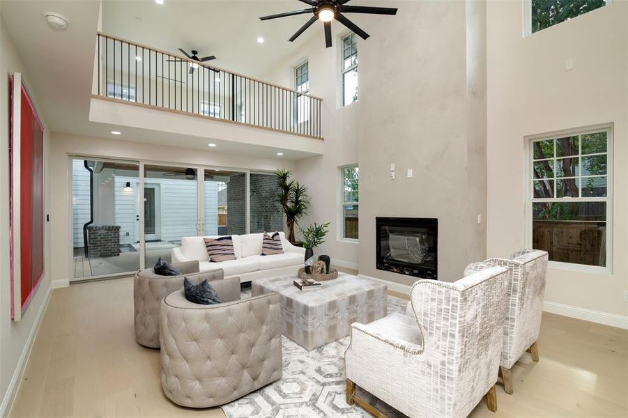 Living room with a towering ceiling, ceiling fan, and light hardwood / wood-style floors