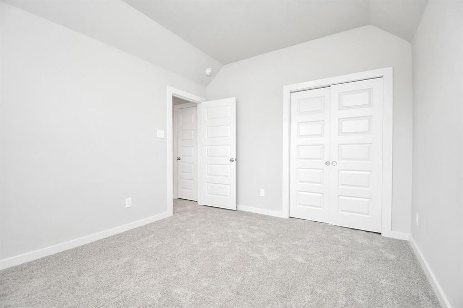 A cozy secondary bedroom with large windows, plush carpet, and spacious closets. The natural light and neutral colors create a serene, inviting atmosphere.