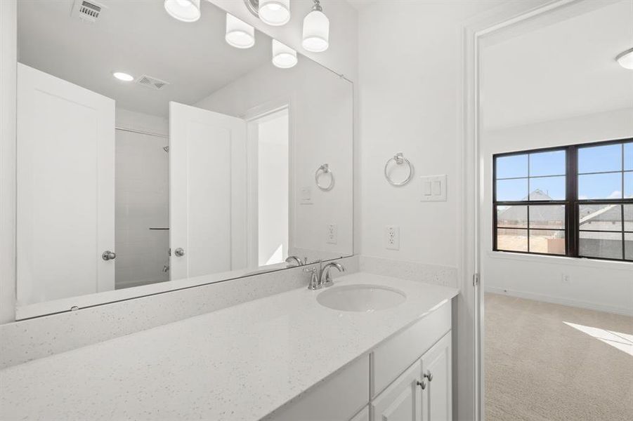 The secondary bath features tile flooring, white cabinetry and light countertops and a shower/tub combo. Perfect for accommodating any visiting family and friends.