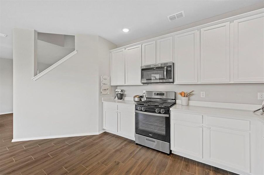 Kitchen featuring white cabinetry, hardwood / wood-style flooring, and stainless steel appliances