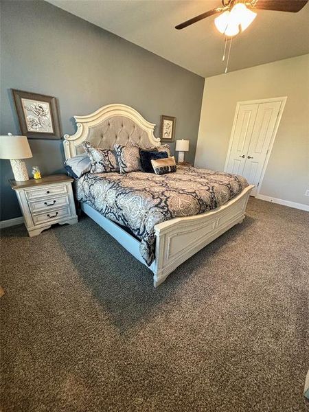 Bedroom with ceiling fan, a closet, and dark carpet