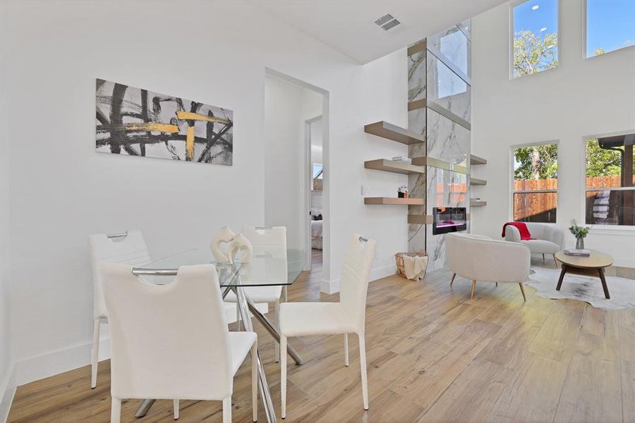 Dining room featuring a towering ceiling, light wood-type flooring, and a healthy amount of sunlight