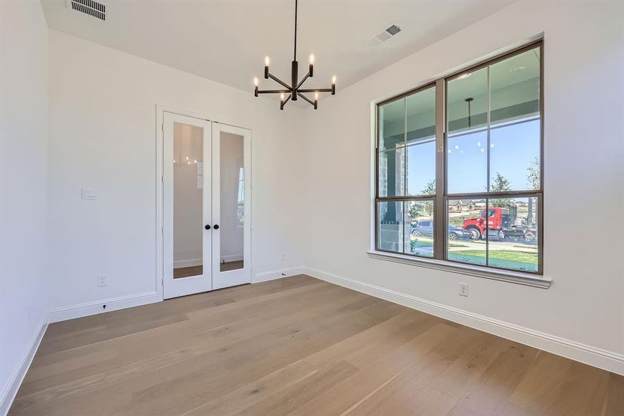 Study with a chandelier, light hardwood / wood-style flooring, and glass french doors