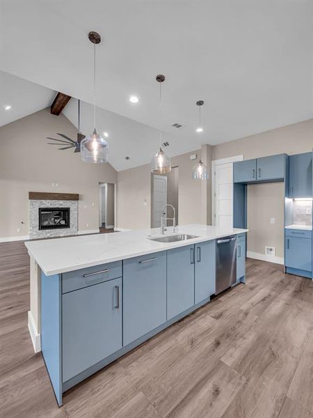 Kitchen with a spacious island, blue cabinetry, lofted ceiling with beams, and sink