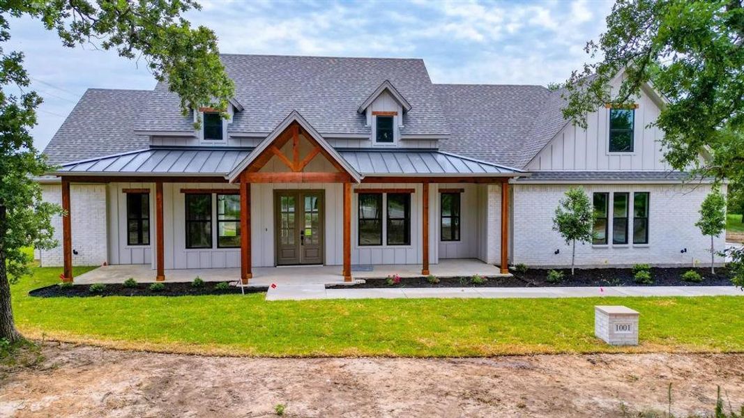 Modern farmhouse style home with a porch and a front yard