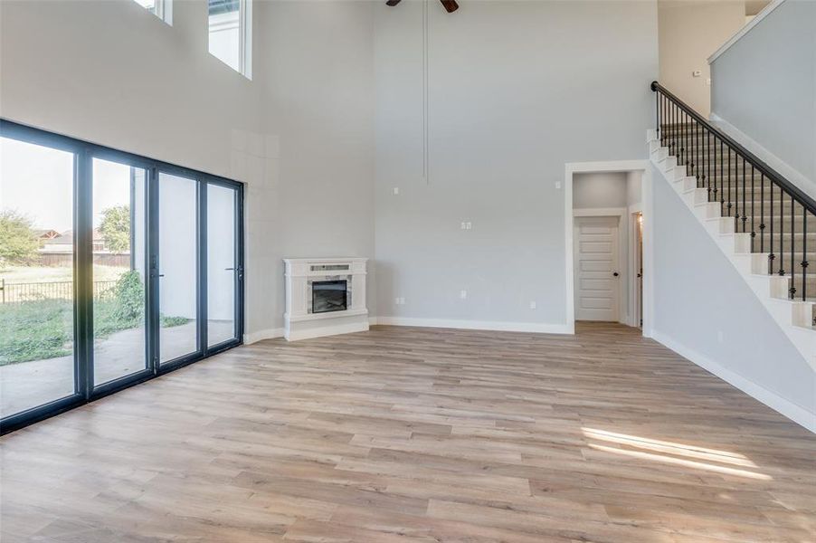 Unfurnished living room with a healthy amount of sunlight, a high ceiling, light wood-type flooring, and ceiling fan