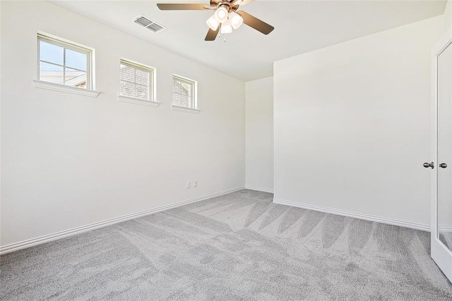 Empty room featuring ceiling fan and light carpet