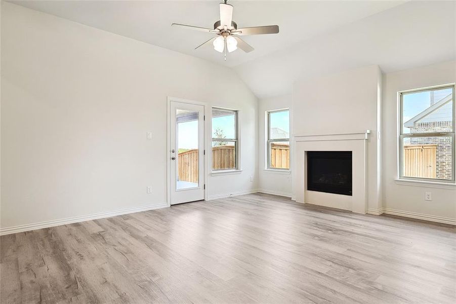 Unfurnished living room featuring vaulted ceiling, ceiling fan, and light hardwood / wood-style flooring