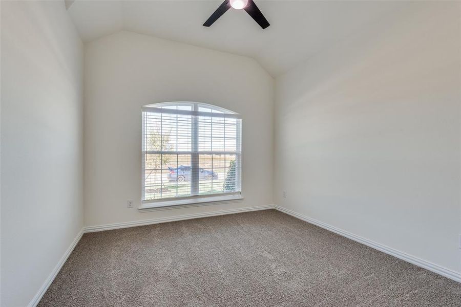 Spare room featuring ceiling fan, carpet flooring, and lofted ceiling