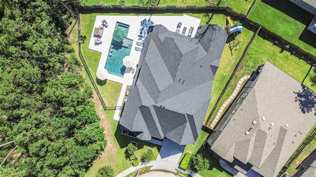 Aerial photo captures a stunning modern house with a luxurious pool, set against a backdrop of lush greenery with no side neighbors on a cul-de-sac lot.