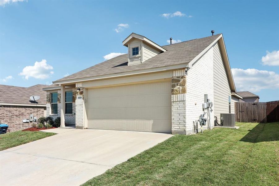 View of front of house featuring central air condition unit, a garage, and a front lawn