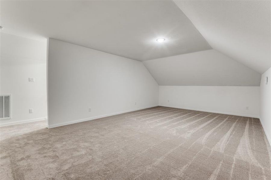 Bonus room featuring lofted ceiling and carpet floors