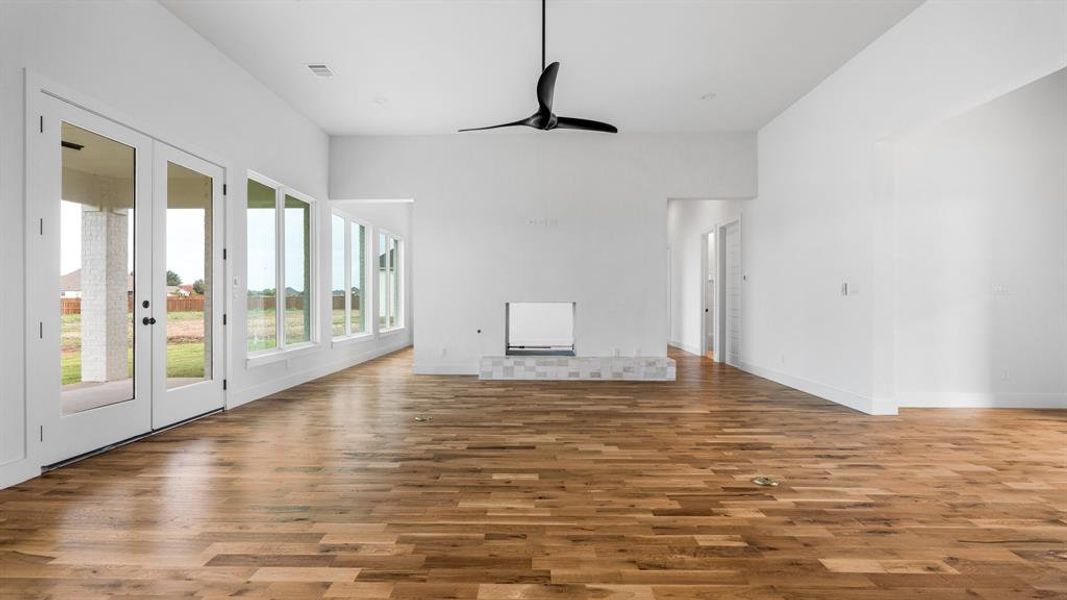 Unfurnished living room with hardwood / wood-style floors, ceiling fan, and a fireplace