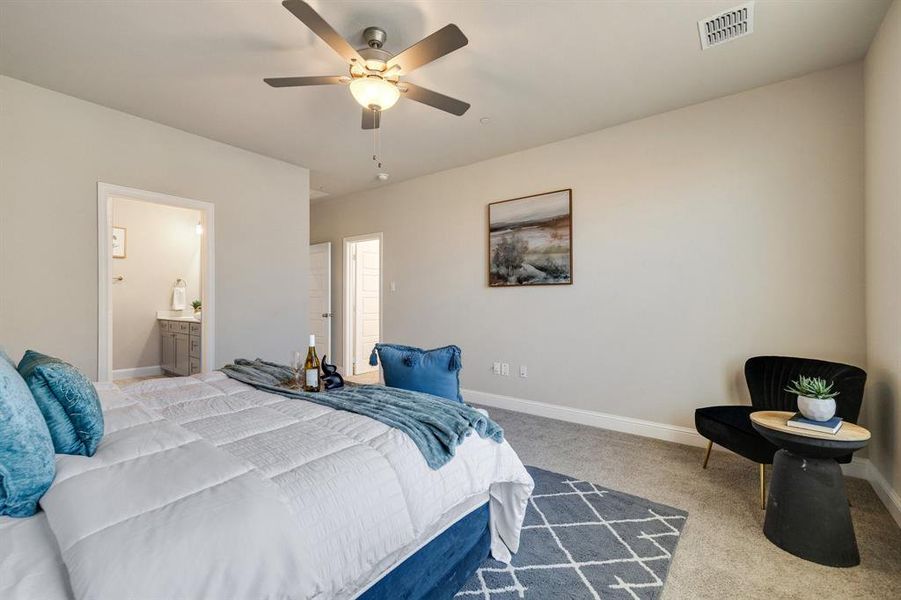 Bedroom with ceiling fan, connected bathroom, and light carpet