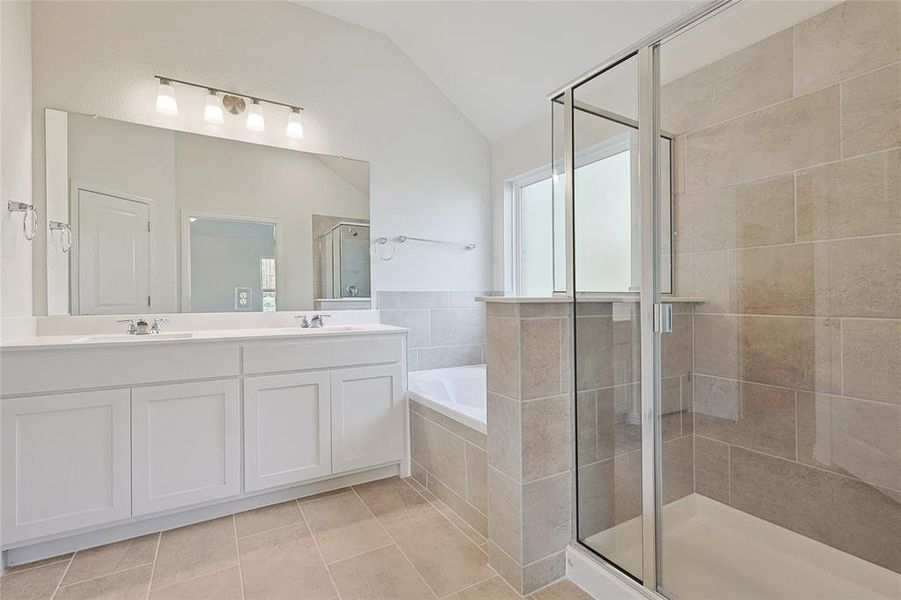 Bathroom with vaulted ceiling, shower with separate bathtub, vanity, and tile patterned floors