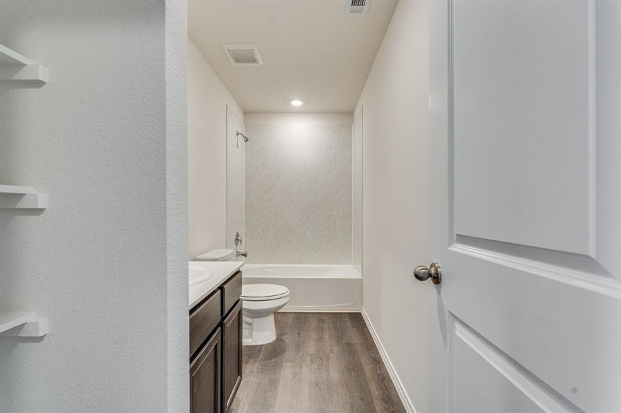 Full bathroom with hardwood / wood-style flooring, shower / washtub combination, vanity, and toilet