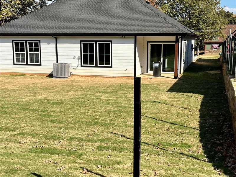 Rear view of house with cooling unit and a lawn