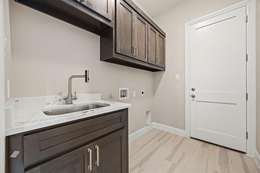 Laundry room with washer hookup, light hardwood / wood-style flooring, sink, and cabinets