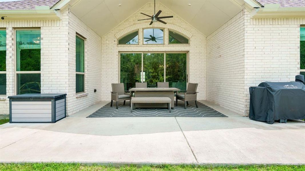 Large ceiling fan on exterior covered patio overlooking large backard