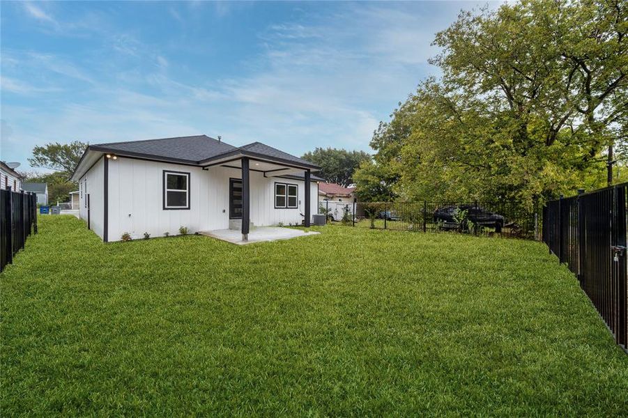 Rear view of house with a patio area, central AC, and a lawn when grass grows.