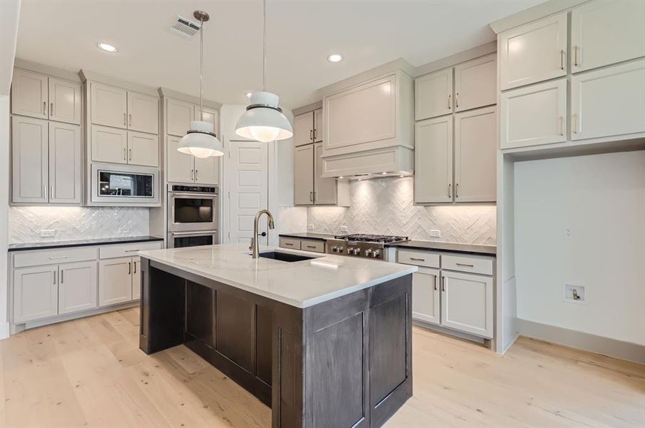 Kitchen featuring appliances with stainless steel finishes, sink, decorative backsplash, and light wood-type flooring