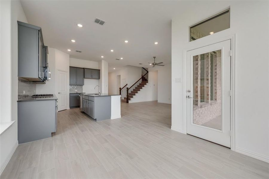 Kitchen with an island with sink, ceiling fan, tasteful backsplash, sink, and gray cabinets