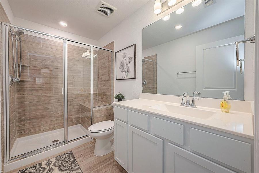 This updated bathroom features a clean design with a shower, toilet and sink.