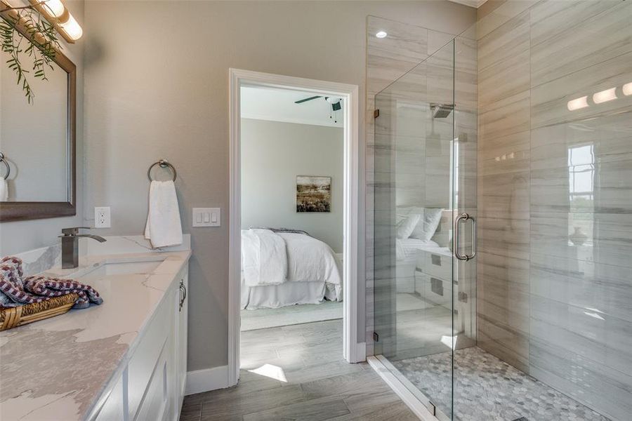 Primary Bathroom featuring wood-type flooring, vanity, and a shower with frameless glass door