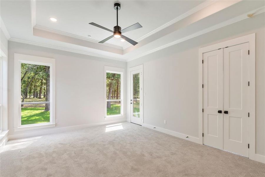 Unfurnished bedroom featuring ceiling fan, carpet flooring, crown molding, and a tray ceiling