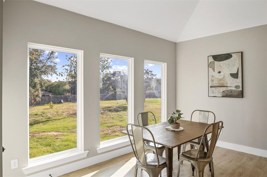 Dining area with light wood-type flooring and vaulted ceiling