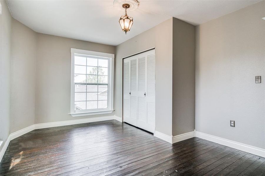 Unfurnished bedroom with dark hardwood / wood-style flooring and a closet