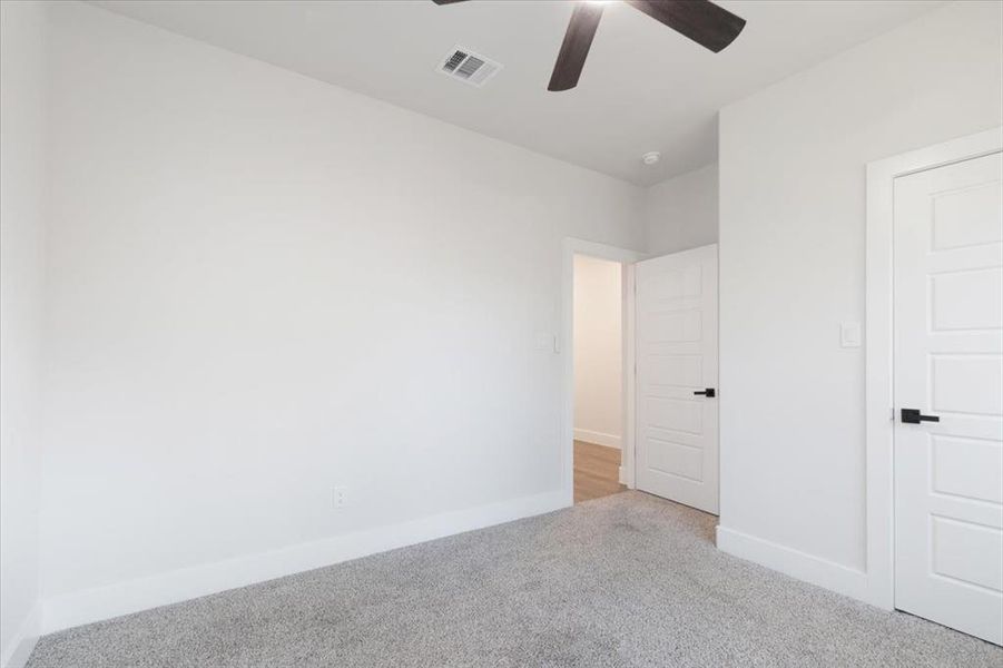 Unfurnished bedroom featuring light carpet and ceiling fan