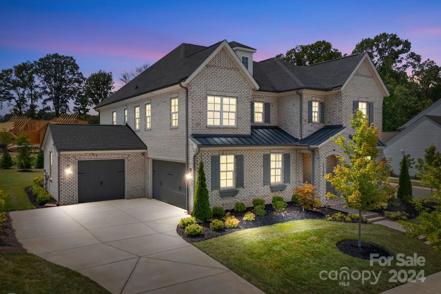 Twilight side view of the property showing the garages and driveway.