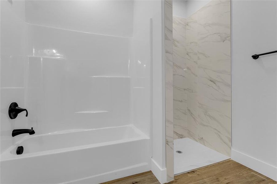 Bathroom featuring hardwood / wood-style flooring and tiled shower / bath