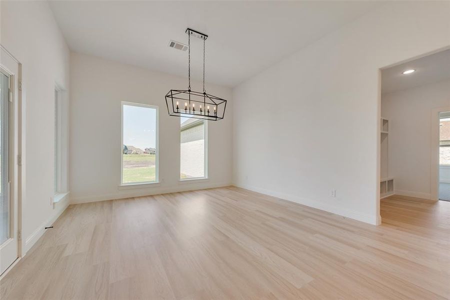 Unfurnished room with a chandelier and light wood-type flooring