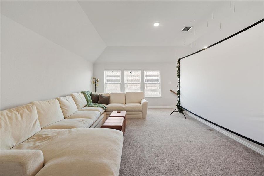 Carpeted second living room with lofted ceiling