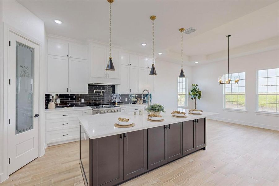 Kitchen featuring white cabinetry, tasteful backsplash, a large island, light hardwood / wood-style floors, and pendant lighting