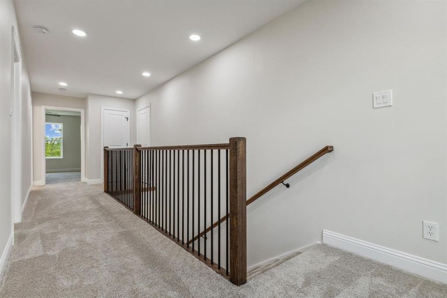 Hallway featuring light colored carpet