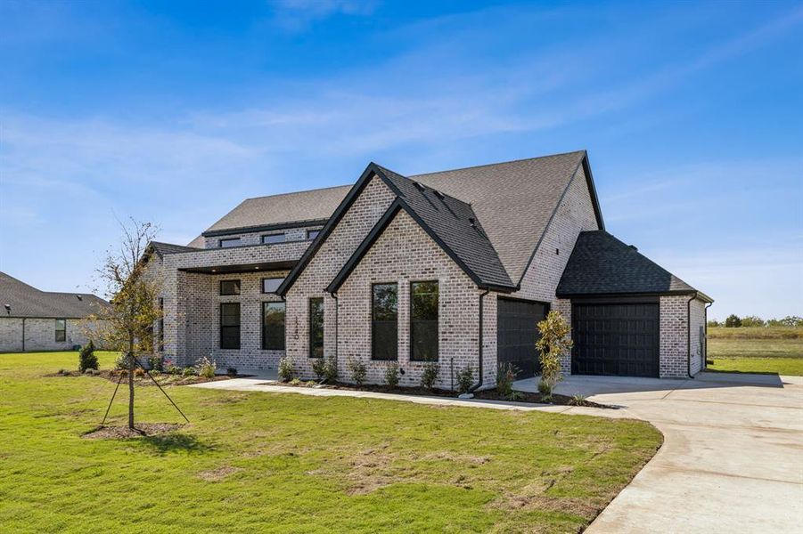 View of front of property featuring a front yard and a garage