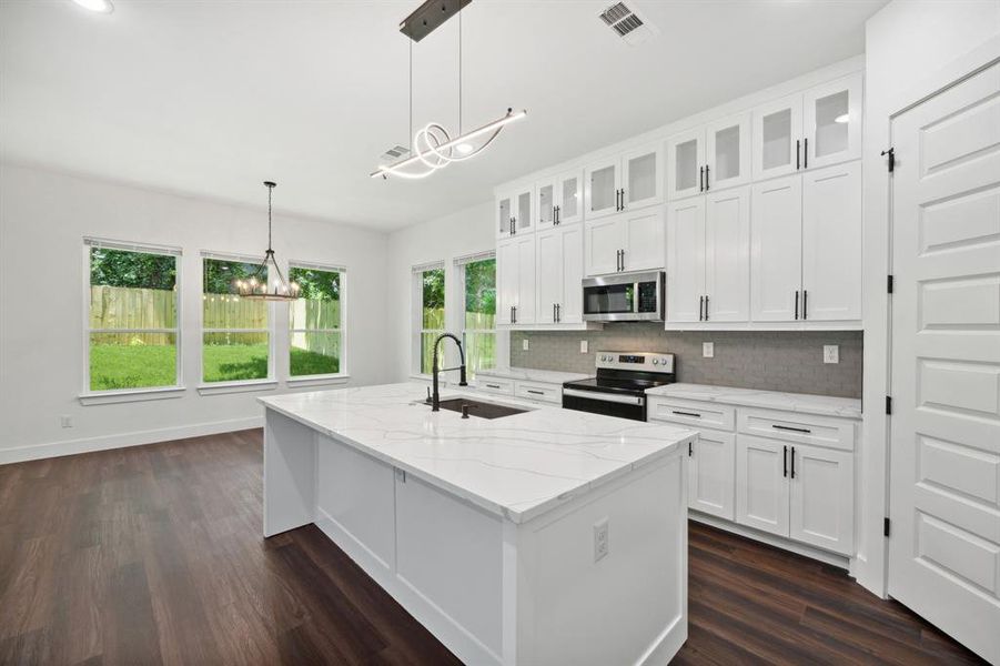 Kitchen with appliances with stainless steel finishes, white cabinetry, dark wood-type flooring, and pendant lighting