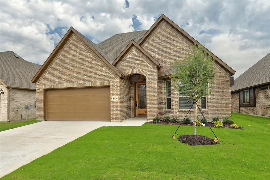 View of front of home with a garage and a front lawn