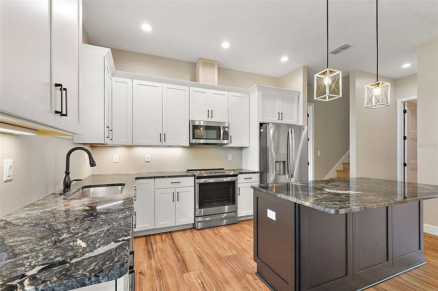Well-appointed kitchen with sparkling ss appliances, prep island and gorgeous Granite counters