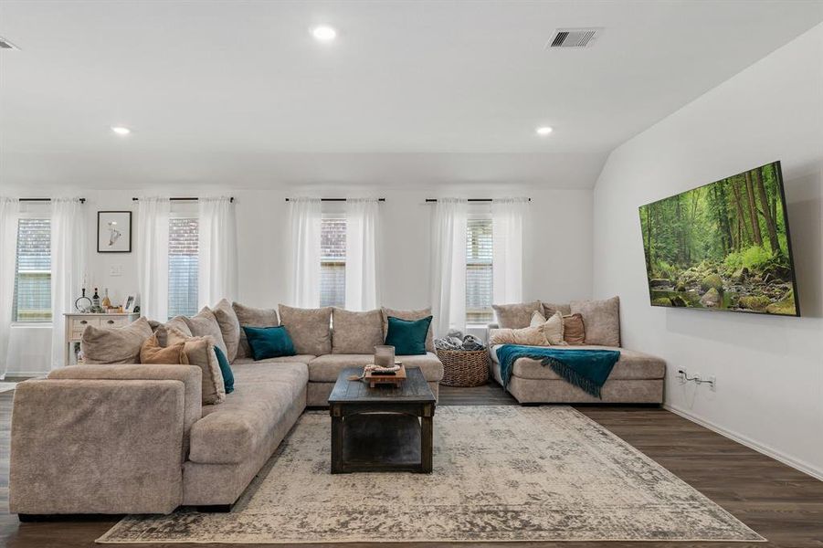 Oversized Great room has lots of windows with blinds and curtains.