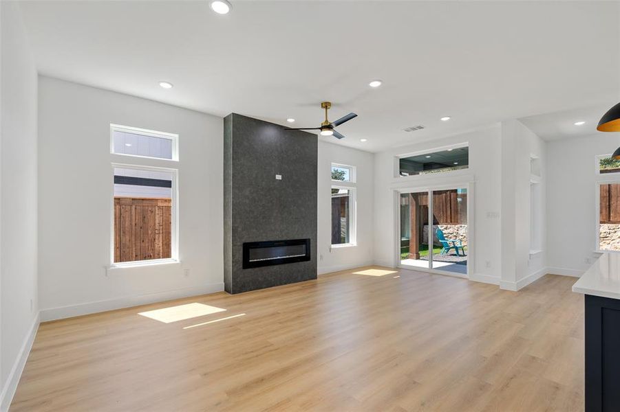 Unfurnished living room featuring light wood-type flooring, a fireplace, and ceiling fan