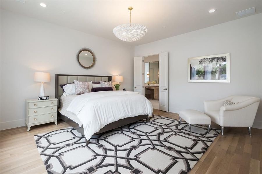 Bedroom featuring an inviting chandelier, light wood-type flooring, and ensuite bath